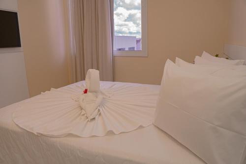 a bedroom with a white bed with two pillows at Hotel Porto Napolis in Eunápolis