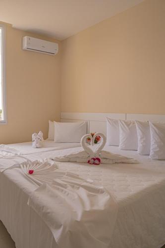 a white bed with a heart decoration on it at Hotel Porto Napolis in Eunápolis
