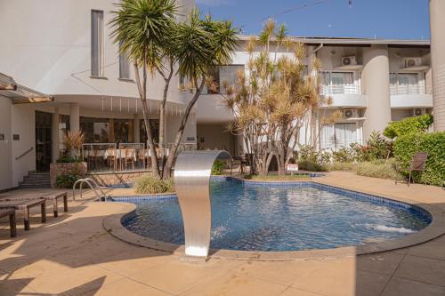 a swimming pool in front of a building at Hotel Porto Napolis in Eunápolis