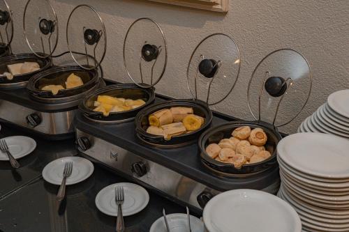 two trays of food on a table with plates and forks at Hotel Porto Napolis in Eunápolis