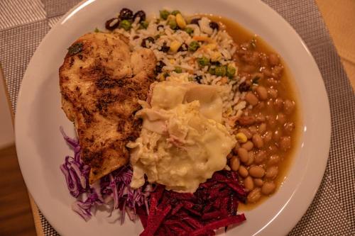a plate of food with chicken and beans and rice at Hotel Porto Napolis in Eunápolis