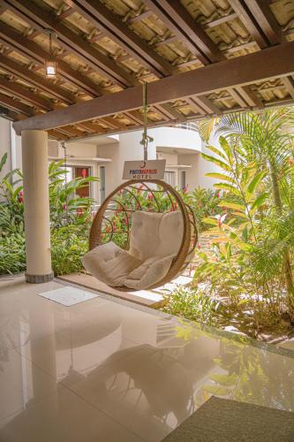 a wicker chair sitting on a patio with plants at Hotel Porto Napolis in Eunápolis