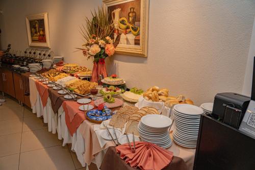 a long table with plates and food on it at Hotel Porto Napolis in Eunápolis