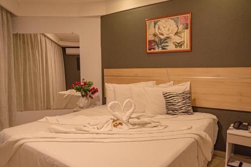 a bedroom with a bed with white sheets and a mirror at Hotel Porto Napolis in Eunápolis