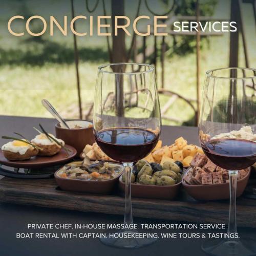 two glasses of wine sitting on a table with food at Endless Sunset with Concierge Services in Marble Falls