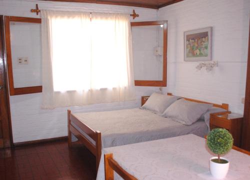 a bedroom with two beds and a window and a table at Bungalows Archi in Termas del Daymán