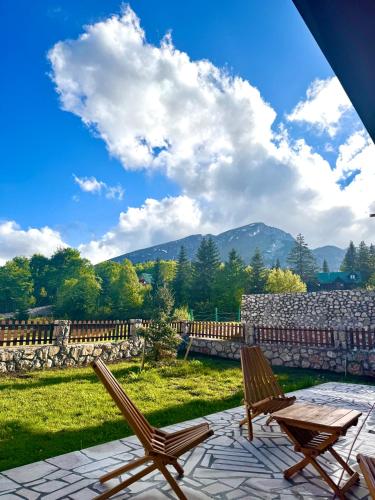 two chairs and a table on a patio with mountains in the background at North Forest in Žabljak