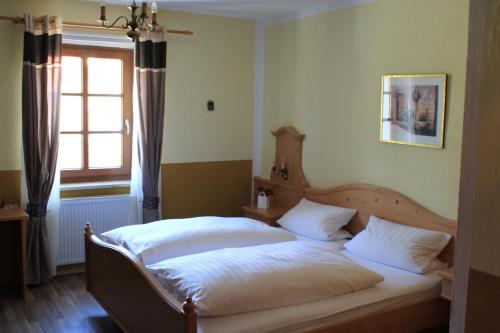 a bedroom with a bed with white sheets and a window at Landhotel Kahrmühle in Pressath
