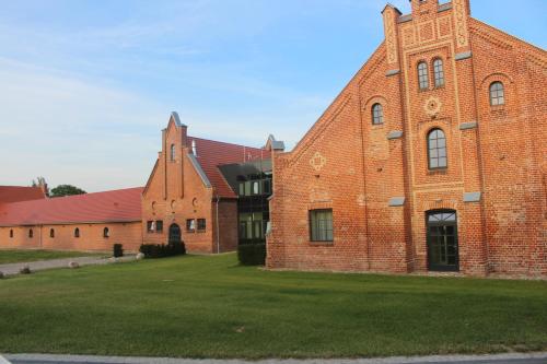 a large brick building with a grass field in front at Farmer Hotel Basedow in Basedow
