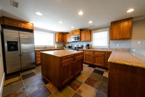 a kitchen with wooden cabinets and a stainless steel refrigerator at Watermen's Hideout - Waterfront 2-Bed, 1-Bath Cottage with HOT TUB & Private Dog Run! in Waves