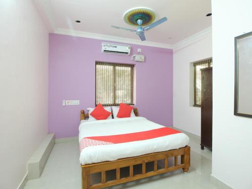 a bedroom with purple walls and a bed with red pillows at JMS Brahmin Guest House Thirunallar in Thirunallar