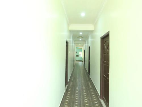 a corridor of a building with white walls and a long hallway at JMS Brahmin Guest House Thirunallar in Thirunallar
