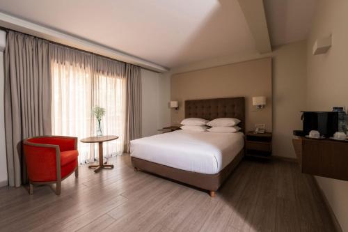 a hotel room with a bed and a red chair at InterContinental Mzaar Lebanon Mountain Resort & Spa by IHG in Kfardebian