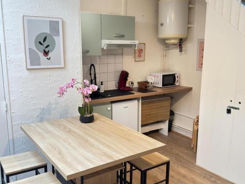une cuisine avec une table en bois et des fleurs. dans l'établissement Cosy Pop'Appart, au Havre