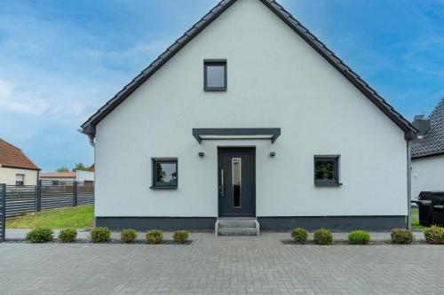 a white house with a black door at Lara Villa in Zepkow