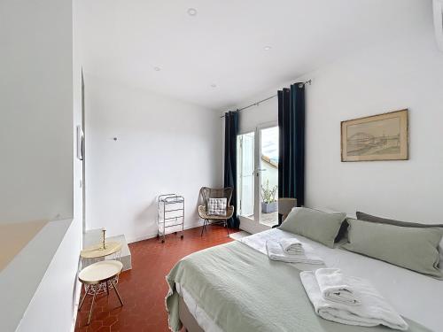 Un dormitorio blanco con una cama y una ventana. en Les Verdalettes, en Saint-Paul-de-Vence