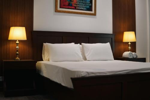 a bedroom with a bed with white sheets and two lamps at Penta Square Executive City View Apartments DHA - Phase 5 Lahore in Lahore