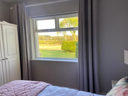 a bedroom with a window and a bed with a bedspread at Tranquil Haven Home in Milltown