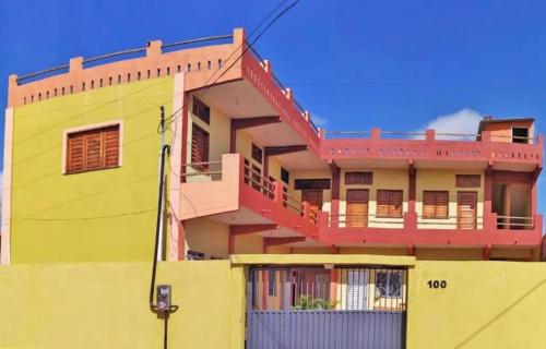 a yellow building with red balconies on top of it at Casa Encanto do Mar Emboaca in Trairi