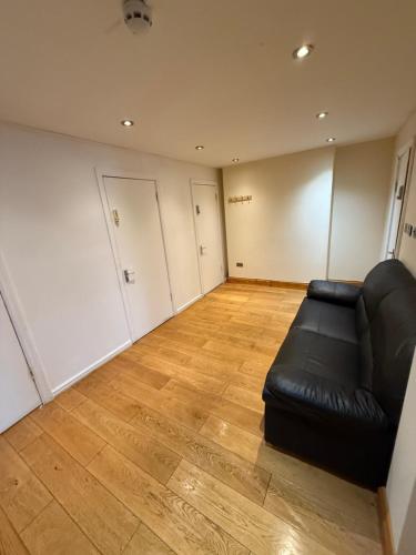 a living room with a black couch and a wooden floor at Charming Stay House in Ealing