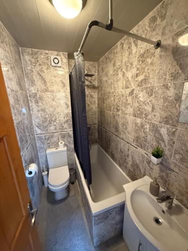 a bathroom with a toilet and a tub and a sink at Charming Stay House in Ealing