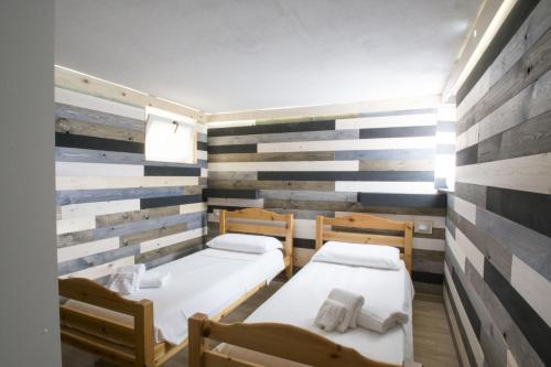 two beds in a room with wooden accent walls at La DaMa in Germignaga