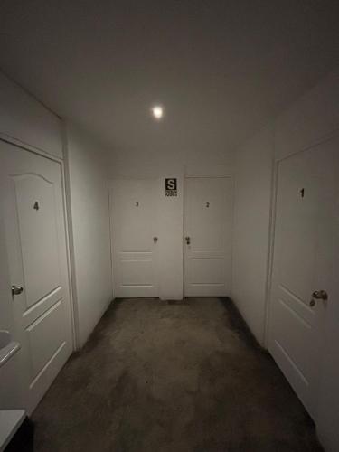an empty room with white doors and concrete floors at Killamoon House Paracas in Paracas