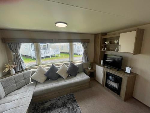 a living room with a couch and a television at Golden Sands Getaways Weymouth in Wyke Regis
