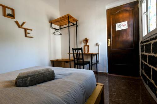 a bedroom with a bed and a wooden door at Drago Hostel in Icod de los Vinos