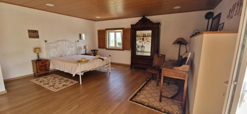 Schlafzimmer mit einem Bett, einem Tisch und einem Kühlschrank in der Unterkunft Casas Cor de Rosa in São Martinho das Moitas