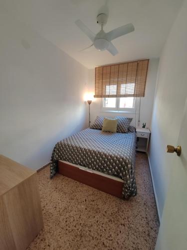 a bedroom with a bed with a ceiling fan at Au bord de la plage in Puerto de Sagunto