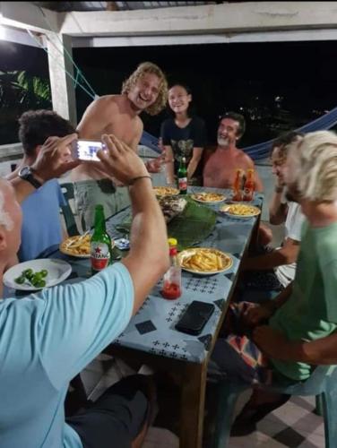 a group of people sitting around a table eating food at Lilys Nias Surf Camp in Lagudri