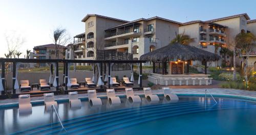 a swimming pool with chairs and a hotel at Grand Solmar Pacific Dunes Resort, Golf & Spa in Cabo San Lucas