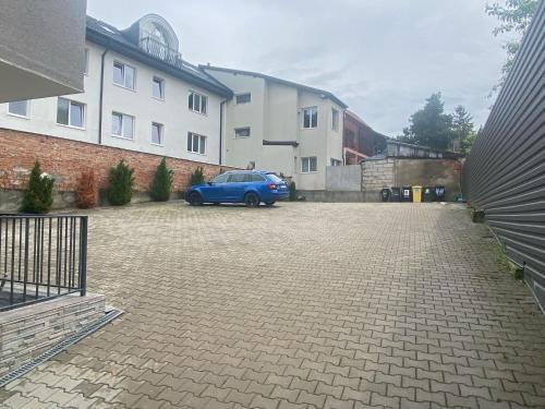 a blue car parked in a parking lot next to a building at Pension Mora in Cluj-Napoca