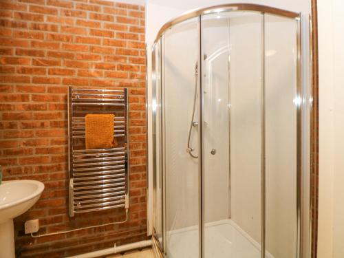 y baño con ducha y pared de ladrillo. en Woodlands, en Buxton