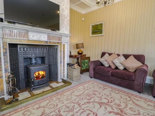 a living room with a couch and a fireplace at Plas Gwynfryn in Llanbedr