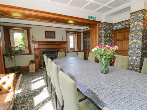 a dining room with a table and chairs and a fireplace at Plas Gwynfryn in Llanbedr