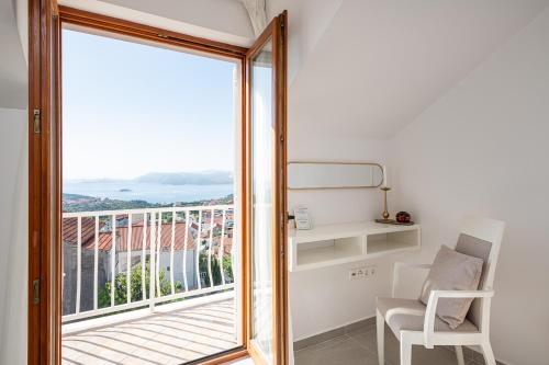a room with a window and a chair and a balcony at Apartments Micika in Cavtat