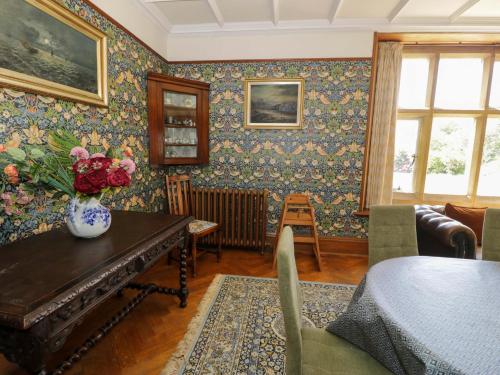 a living room with a table with a vase of flowers at Plas Gwynfryn in Llanbedr