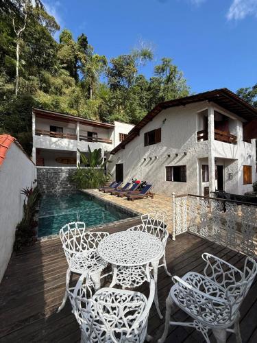 a patio with a table and chairs and a pool at Casas do Luiz Miguel in Caraguatatuba