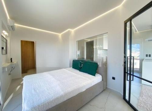 a white bedroom with a bed with a green pillow at GP Castle Patras in Patra