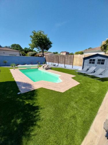 une arrière-cour avec piscine et pelouse dans l'établissement Location en nuitée, à Abeilhan
