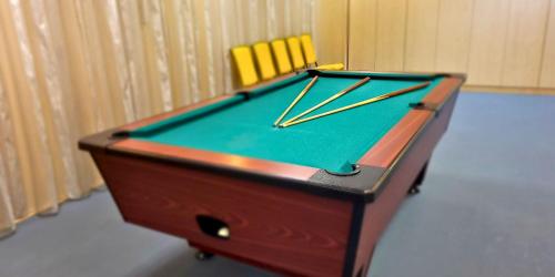 a pool table with cue sticks on top of it at Hungarospa Thermal Hotel in Hajdúszoboszló