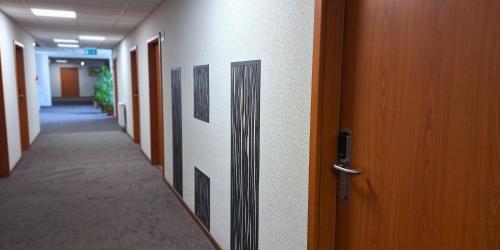 a hallway of an office building with a door and a hallwayngthngthngthngth at Hungarospa Thermal Hotel in Hajdúszoboszló