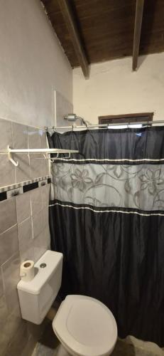 a bathroom with a toilet and a black shower curtain at Casa de Campo in San Isidro