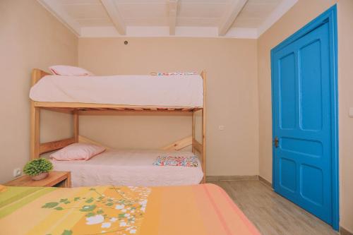 a room with two bunk beds and a blue door at Qiwi House in Ureki