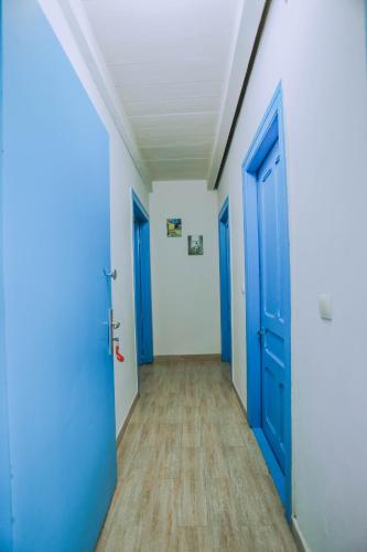 an empty hallway with blue doors and wooden floors at Qiwi House in Ureki