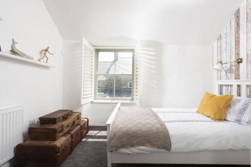 een witte slaapkamer met een bed en een raam bij Piskey Cottage, Mousehole - Close to Harbourside - Free WiFi - Free Parking in Mousehole