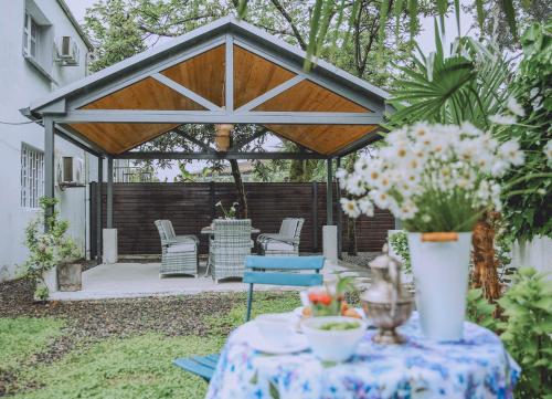 a gazebo in the backyard with a table and flowers at Qiwi House in Ureki