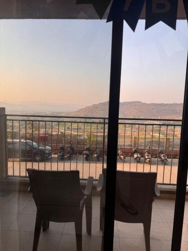 a balcony with two chairs and a view of a parking lot at Rosho homes in Pirangut